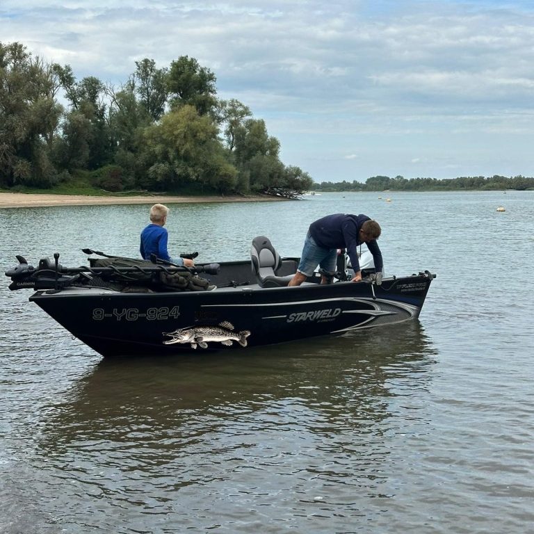 Visgids Dutch Fishing Experience Twee mensen op een vissersboot in een rivier, bezig met hun visuitrusting.